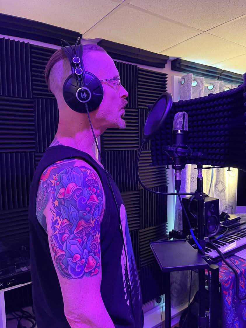 Jay Miller in studio lighting showing mushroom and crystal tattoo sleeve